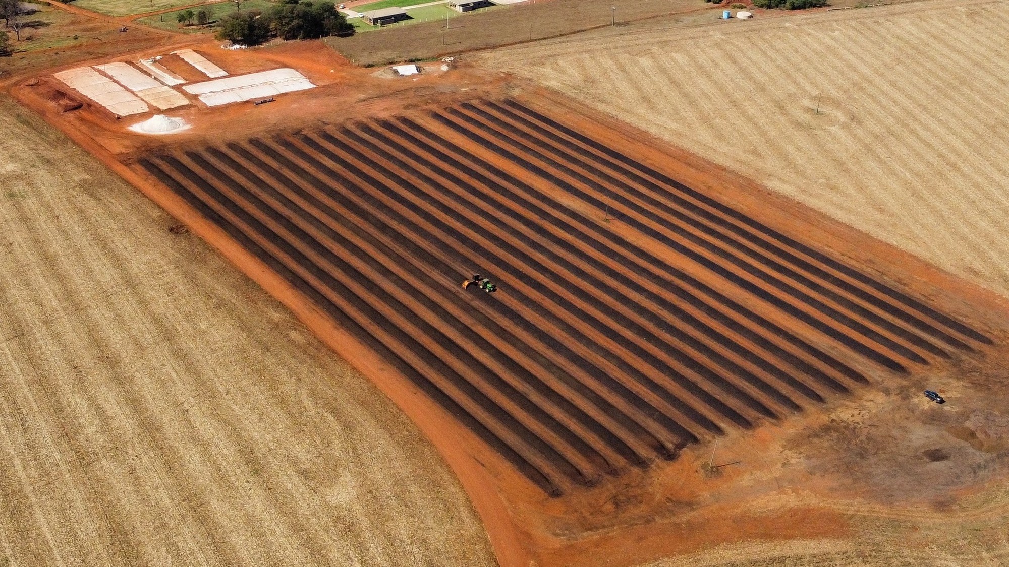 Vista aérea do pátio de compostagem Padrão Libertas com leiras e trator revolvedor